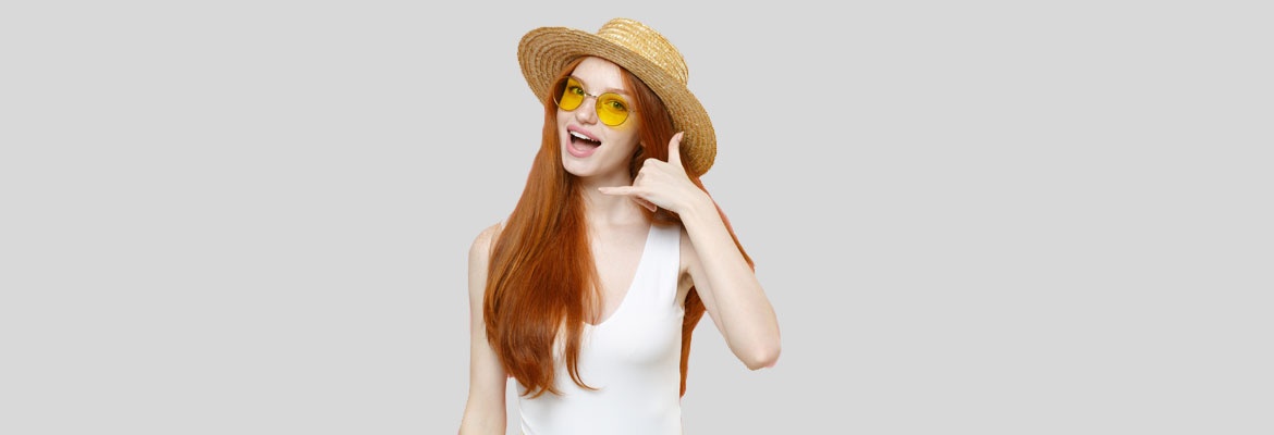 junge Frau mit Sonnenbrille und Sonnenhut telefoniert